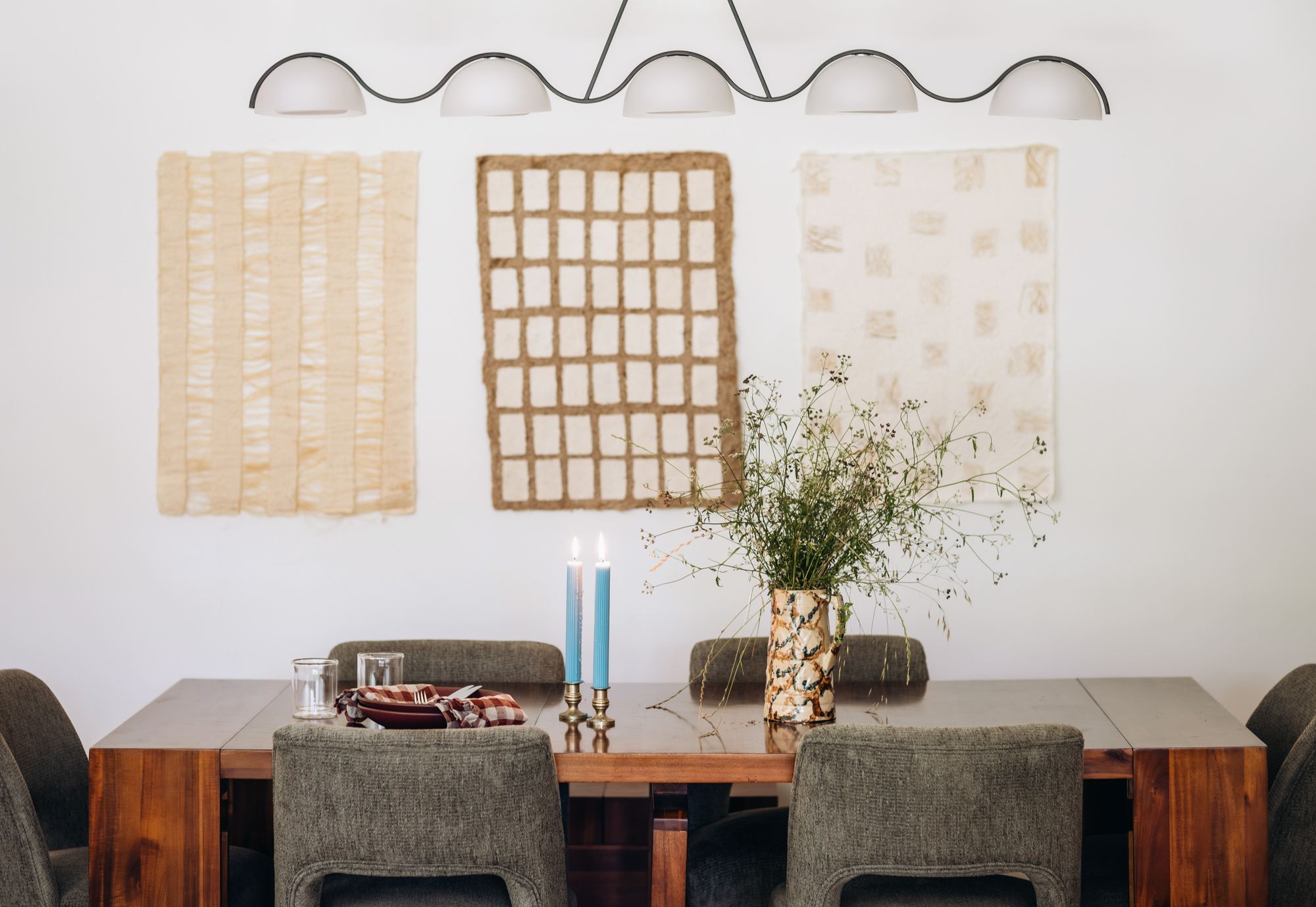 Dining room with a sculptural pendant light and woven wall art