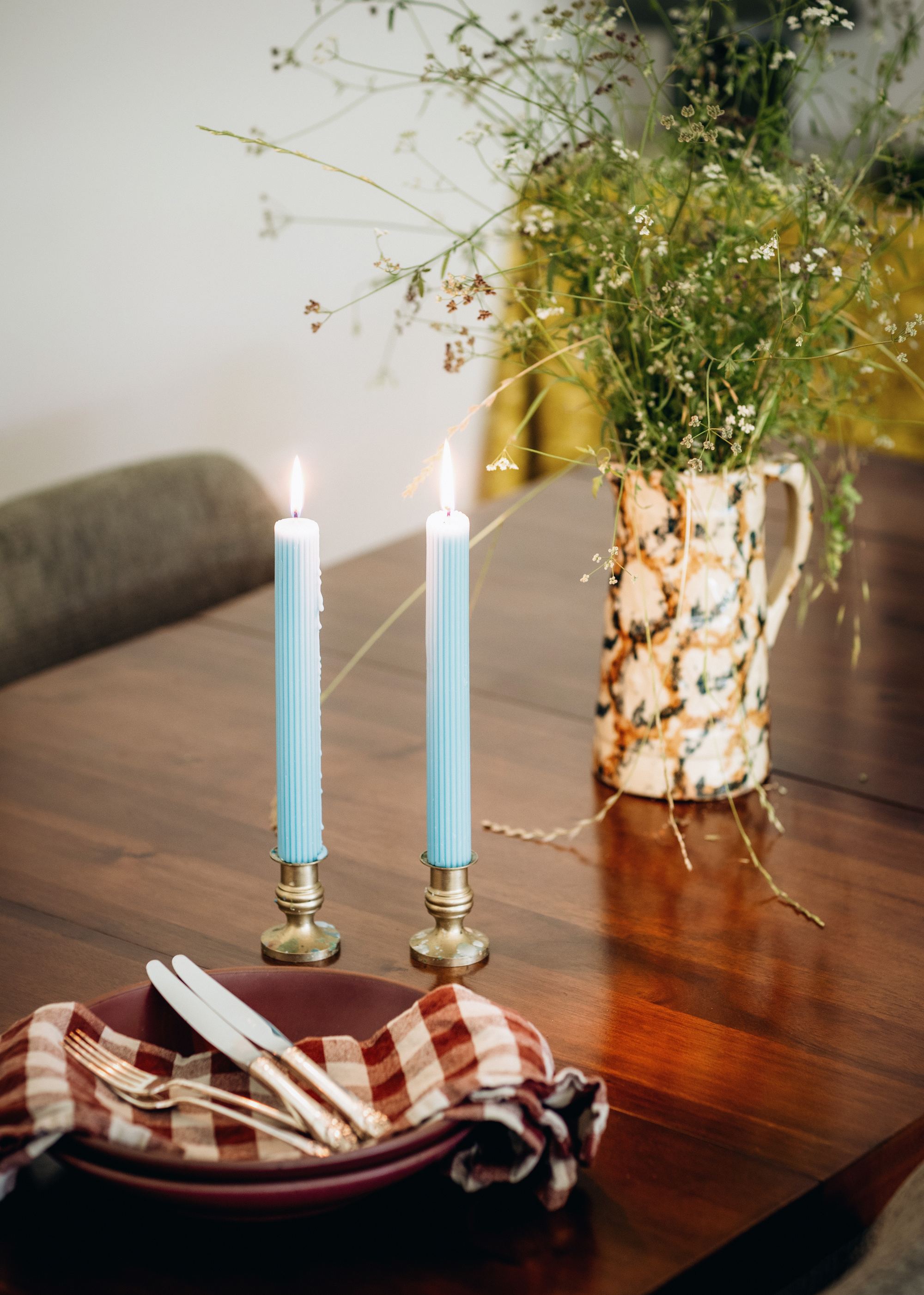 Dining table detail with taper candles and a wildflower arrangement
