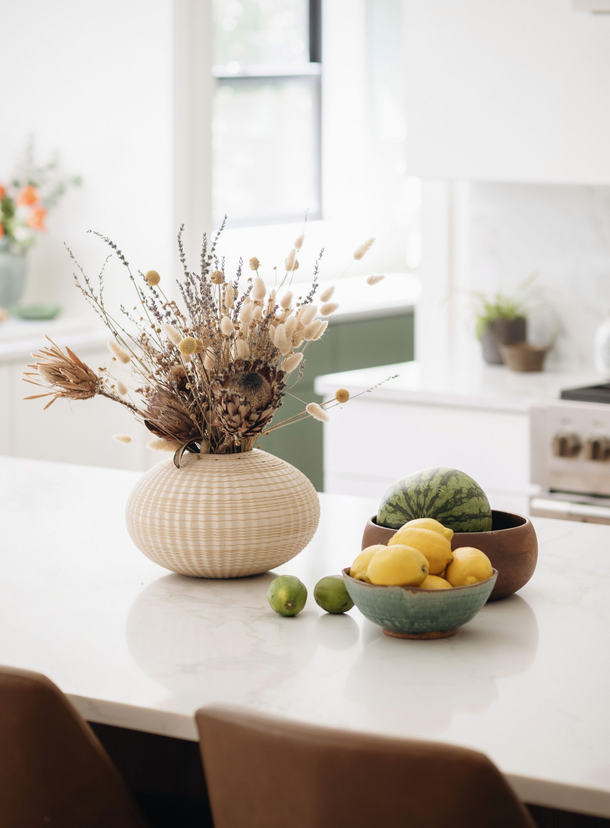 Kitchen island with a dried flower arrangement and fruit bowls