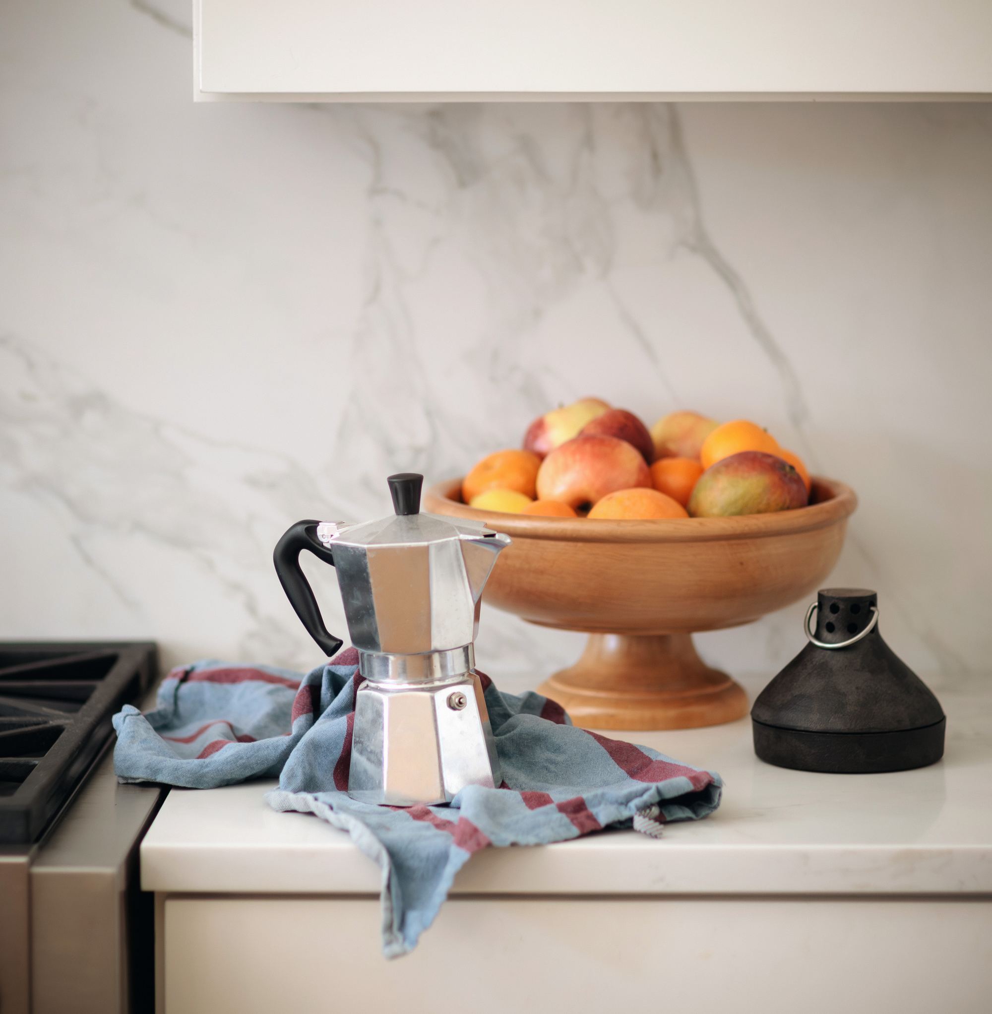 Kitchen counter styling with a marble backsplash and stovetop espresso maker