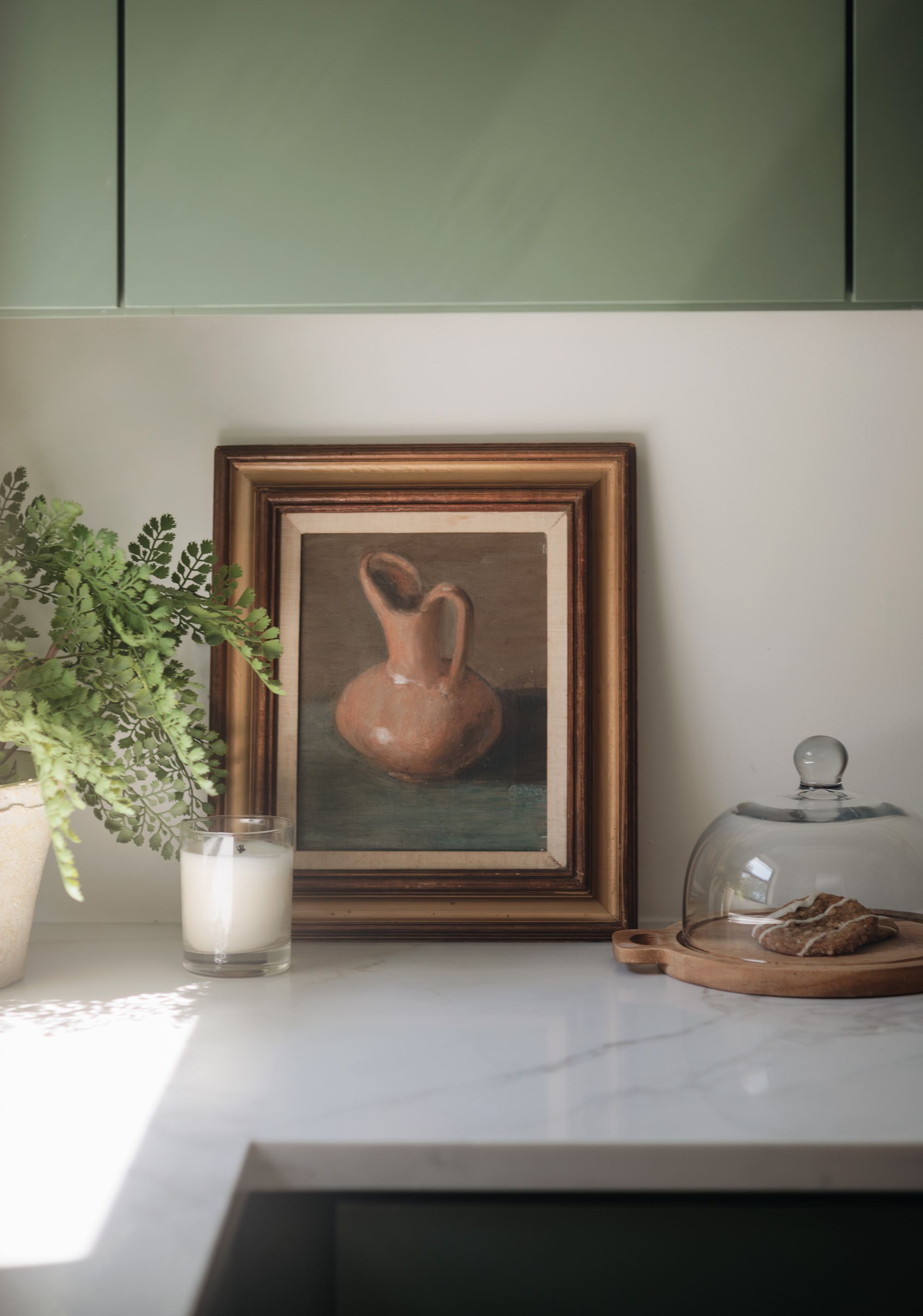 Kitchen counter styling detail with framed art and greenery