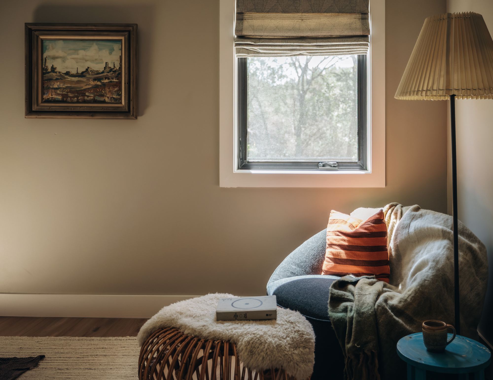 Reading corner with a pleated floor lamp and layered textiles