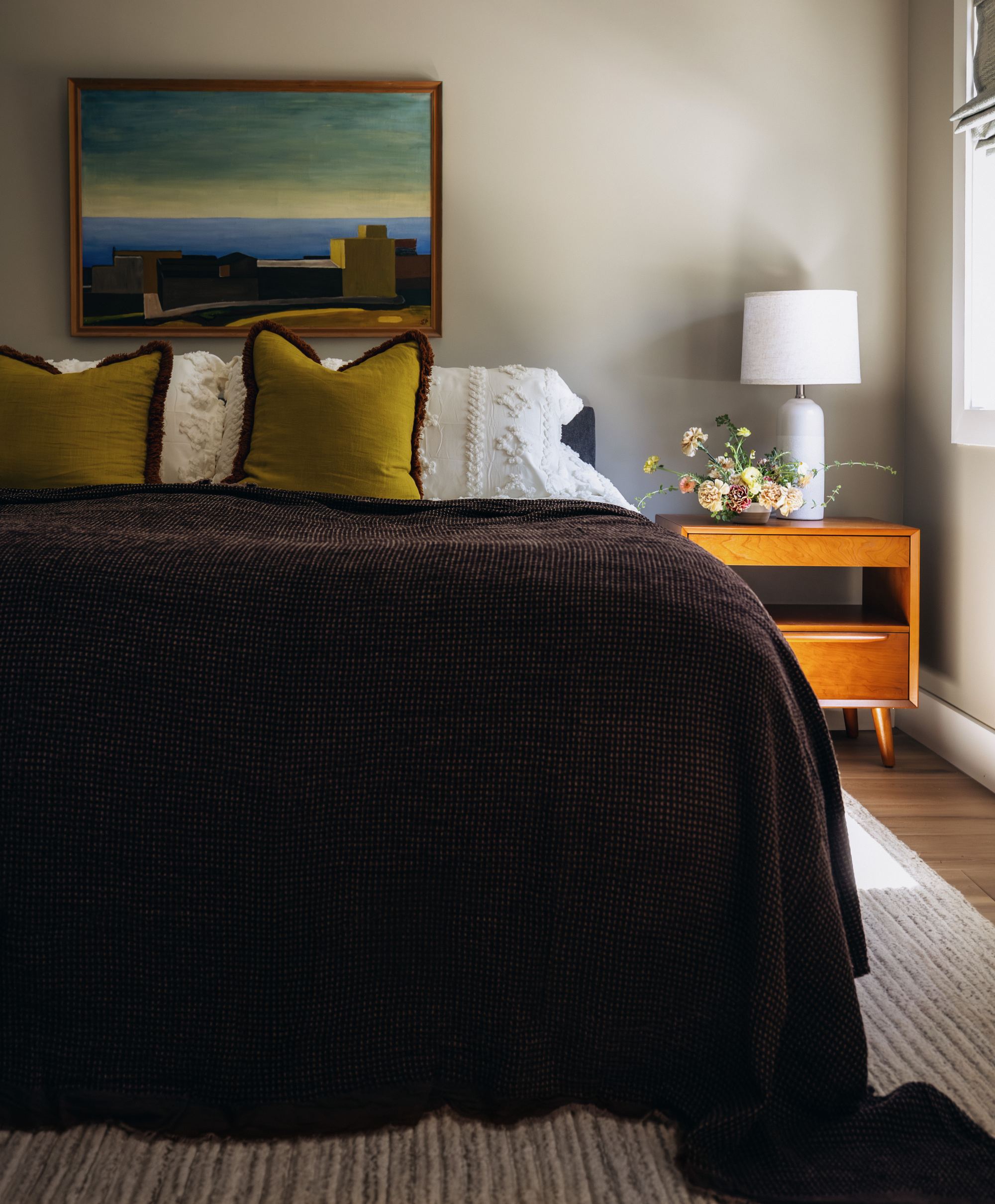Primary bedroom with a mid-century nightstand and framed landscape art