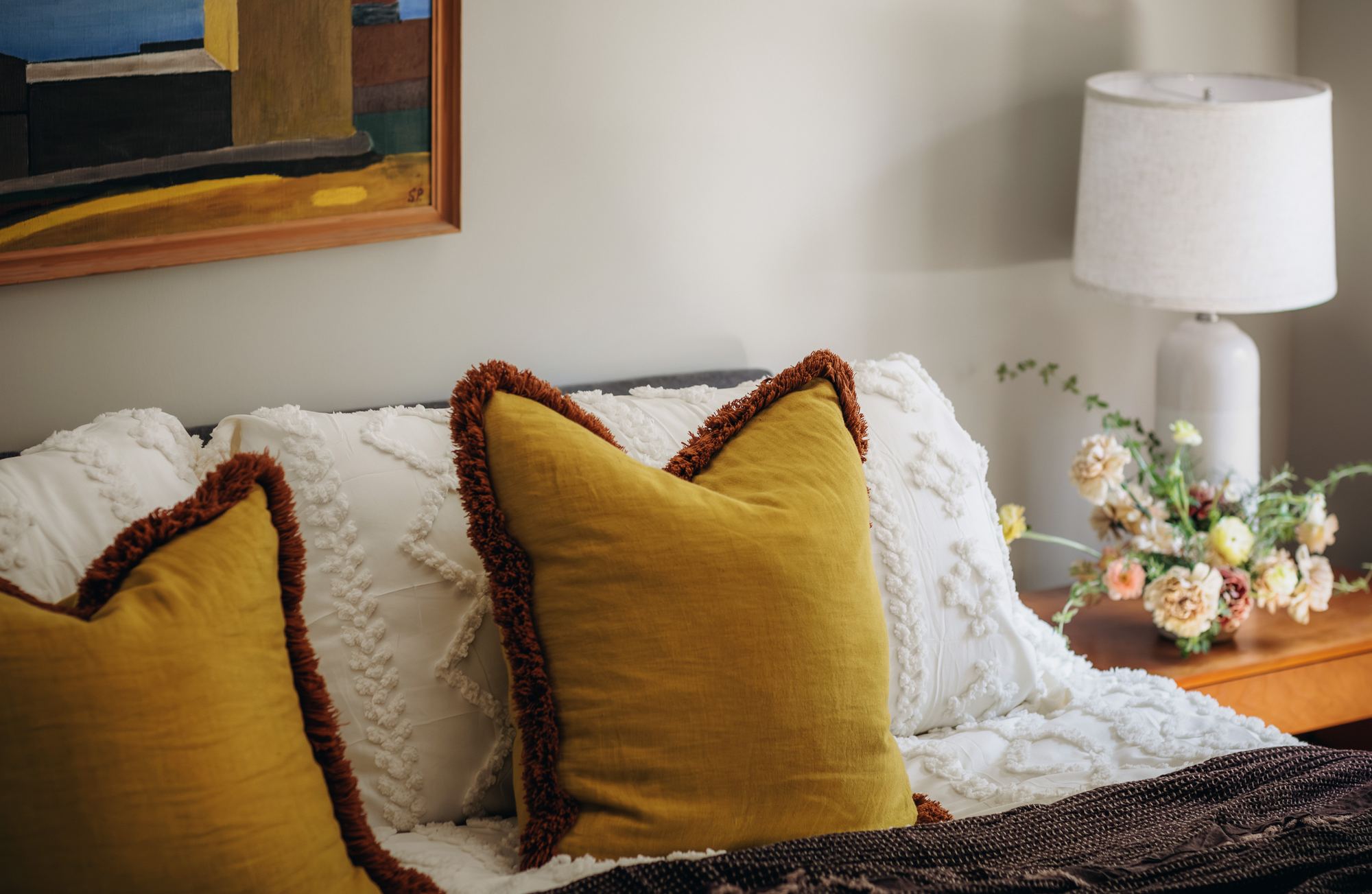 Bedroom detail with mustard velvet pillows and fresh flowers