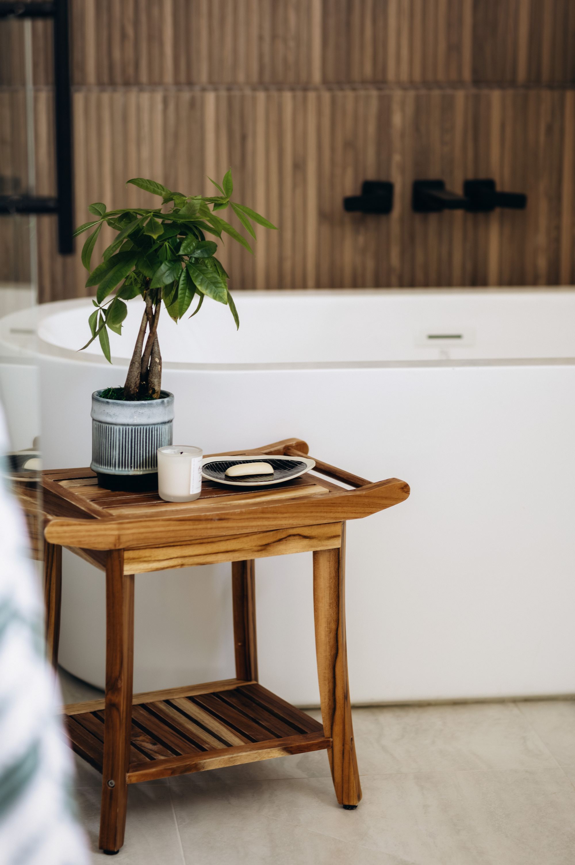 Bathroom styling with a teak bath caddy and potted plant