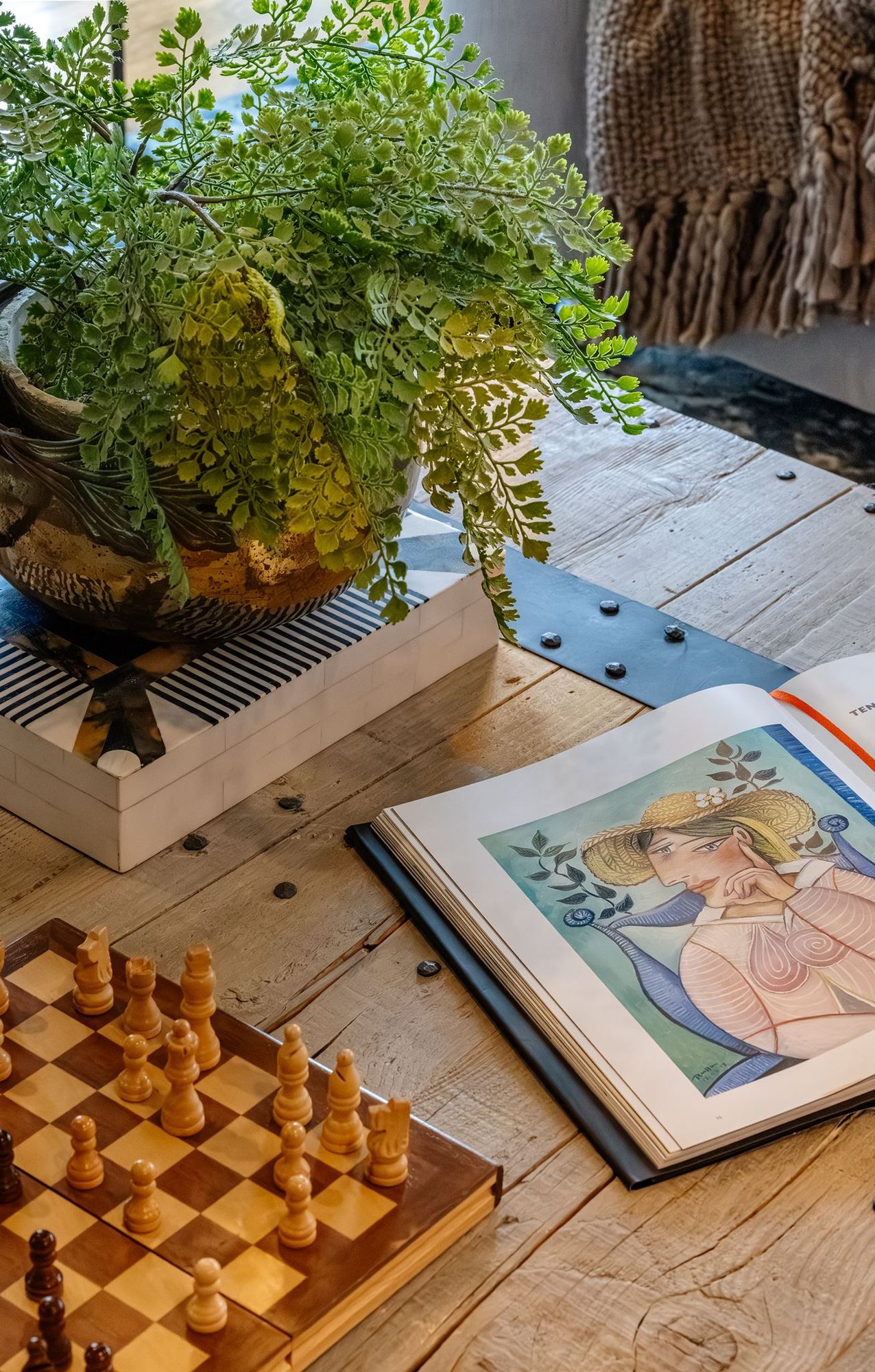 Coffee table styling with a fern, chess set, and art book